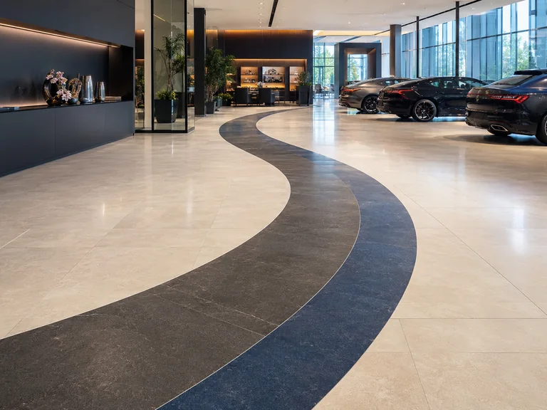 Hall de concession avec carrelage à motif courbe bicolore découpé au jet d’eau